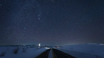 a road in winter, the sky full of stars