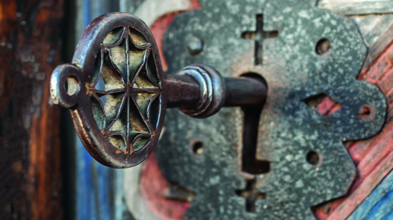 Closeup detail view of old massive metal key in a large huge church wooden ancient door. Secret mystery entrance. Traditional gothic grunge vintage style. Medieval security and safety