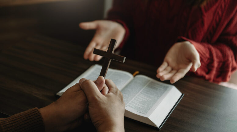 Woman's hand with cross .Concept of hope, faith, christianity, religion, church and pray to God. on the wooden table