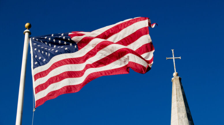 American flag and church steeple against very clear blue sky