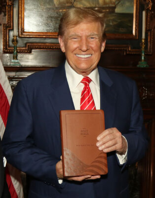 A picture of former president donald trump holding the god bless the usa bible.