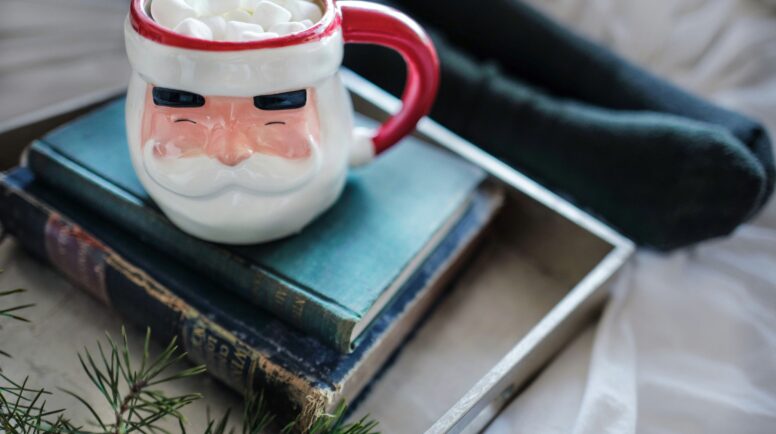 a pile of books with a santa clause mug on top