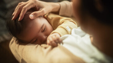 High Angle Portrait of a Cute Asian Baby Feeding from the Breast of Her Mother. Intimate Moment Between New Mother and Infant Showing Motherly Love, Tenderness, and Unconditional Affection.