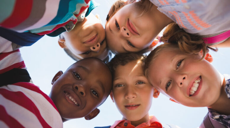 Schoolkids forming huddle in campus at school
