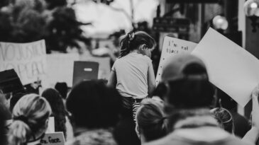A child sits on an adults' shoulders at a protest.