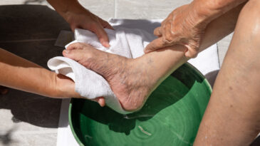 foot-washing prayer. Female caregiver wipes the elderly woman feet by towel.