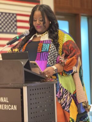 A woman stands behind a lecturn.