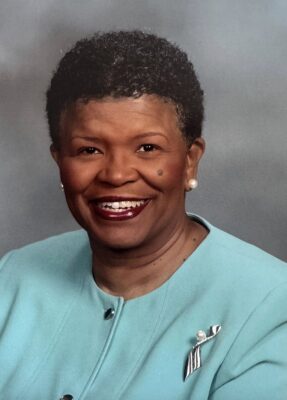 A woman smiles for a headshot, wearing a blue suit.