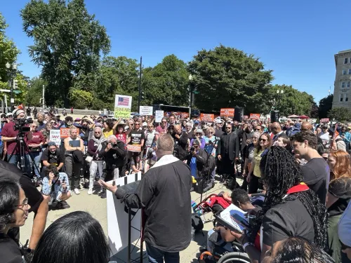 The Rev. Tony Larson opens Moral Monday event with a prayer. Pastor prays in front of a crowd.