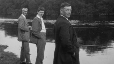 a group of men standing next to a river