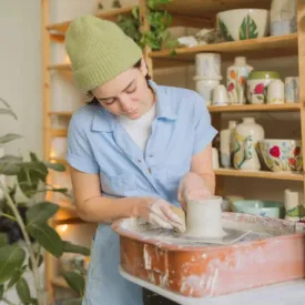 A woman throwing pottery on a wheel