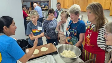 Women standing in the kitchen with raw tortilla dough.