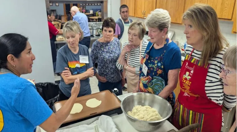 Women standing in the kitchen with raw tortilla dough.