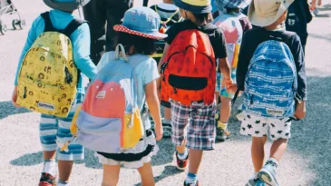 Children walk in a line with backpacks