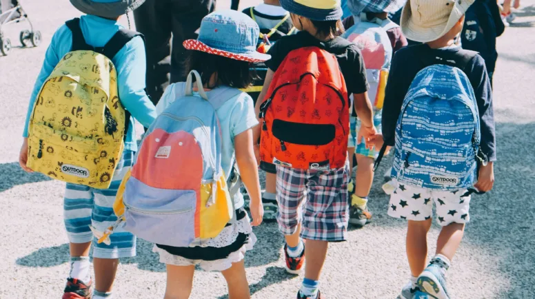 Children walk in a line with backpacks