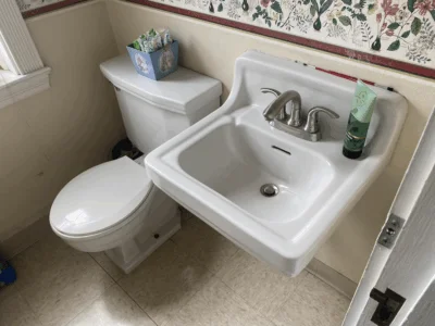 A bathroom in a church with a box of tampons sitting on top of the toilet