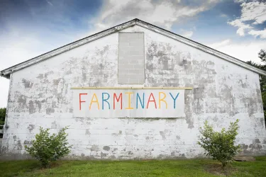 A whitewashed building with a sign that reads "Farminary." The letters are all different colors.