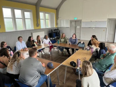 A group of students sit around tables that have been set up in a square.