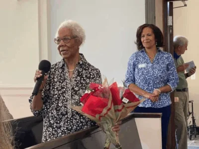 A woman stands up and speaks with a microphone