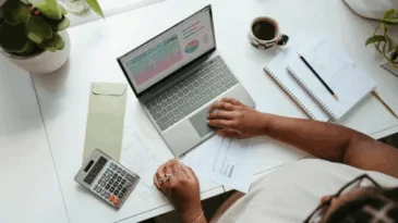 An aerial view of a person sitting at a computer with a calculator