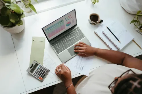 An aerial view of a person sitting at a computer with a calculator