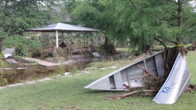 A metal canoe with the Mo Ranch logo on it is wrapped around a tree -- a river in the background.