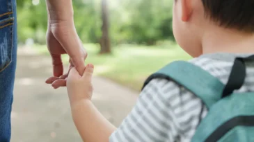 Asian Mother and little son holding hands walking in public park together