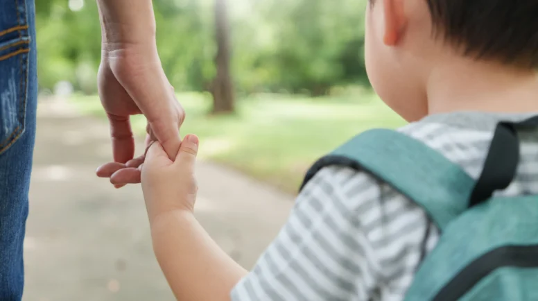 Asian Mother and little son holding hands walking in public park together