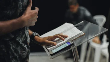 Man standing at a pulpit with his Bible and a phone