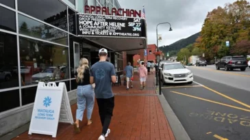 People walk by the Applacian Theatre's marquee promoting Hope After Helene.