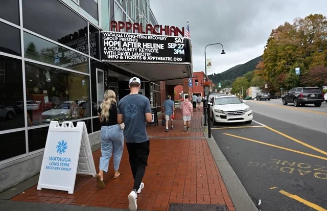 People walk by the Applacian Theatre's marquee promoting Hope After Helene.