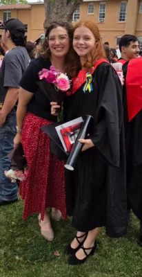 Coach Essie poses with Daria Butenko, who is wearing a graduation cap and gown.