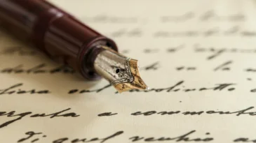 An ink pen lying on a written scroll of paper.