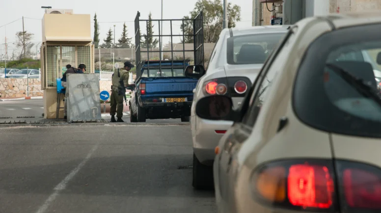 Betlehem, Palestinian Territory - March 3, 2013: A soldier checks cars passing through the Israeli military checkpoint controlling movement between Bethlehem and Jerusalem through the separation wall, March 3, 2013.
