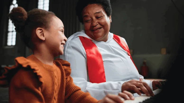 A woman teaching little girl to play piano during performance in church