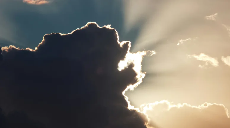 Sun peeking out from behind a dark cloud.
