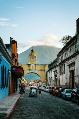 A cobblestone road and old buildings with a giant green mountain in the background