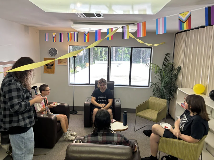 Students sit under a banner that includes the pride, transgender, bisexual, and transsexual flags.