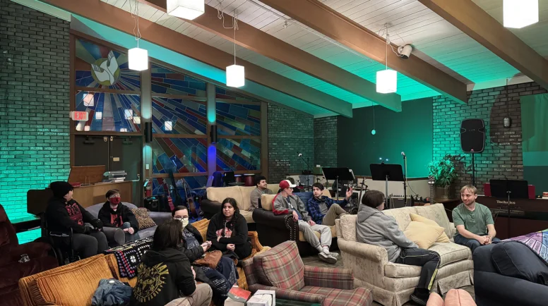 Students sit on couches with stain glass in the background