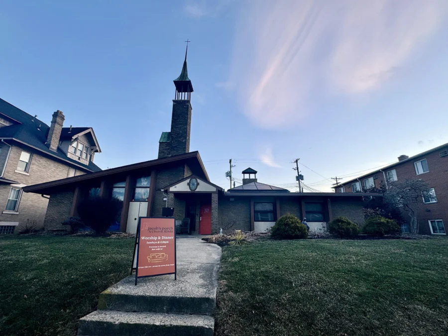 A brick church nestled between a house and an apartment building