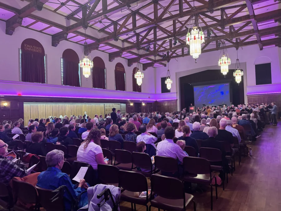 People sit in rows of chairs facing a stage