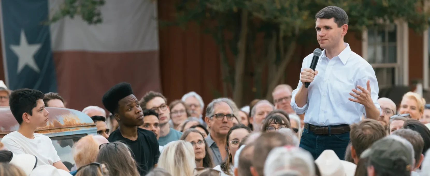 James Talarico stands and talks in a crowd of people.