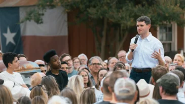 James Talarico stands and talks in a crowd of people.