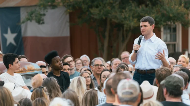 James Talarico stands and talks in a crowd of people.