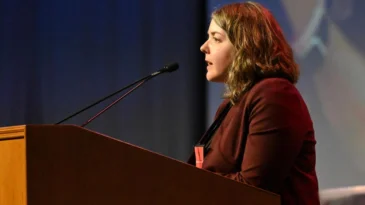 Katie Carter, Director of Faith-Based Investing and Shareholder Engagement for Presbyterian Life & Witness, speaks at a podium