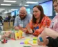 A group of people play at Louisville Center a game around a table