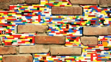 Old bricks are connected and held together by Lego plastic building bricks. This is an example of Dispatchwork, a worldwide street art project started by German artist Jan Vormann.