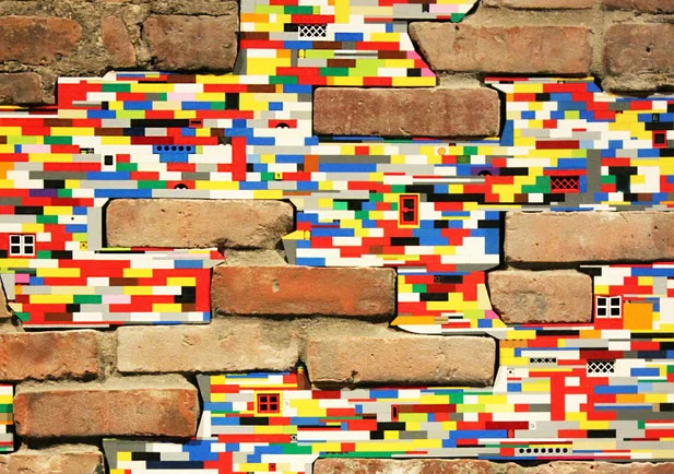 Old bricks are connected and held together by Lego plastic building bricks. This is an example of Dispatchwork, a worldwide street art project started by German artist Jan Vormann.