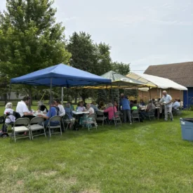 People sitting around tables at the potluck following the church service.