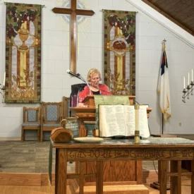 Pastor Cathy Manthei preaching at the pulpit.